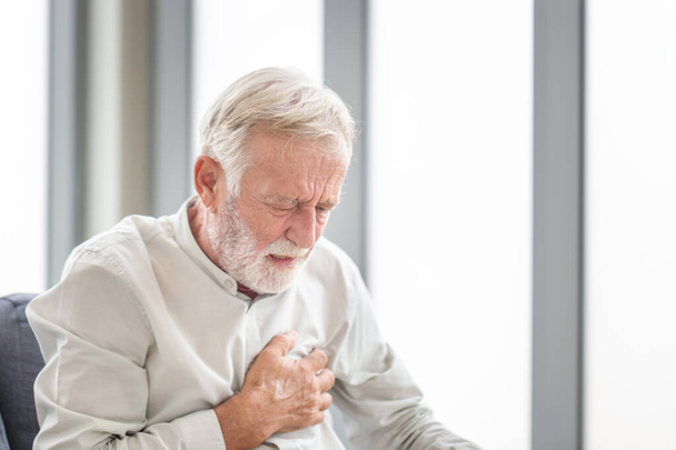 Старший мужчина прижимает руку к груди имеет сердечный приступ страдает от невыносимой боли, зрелый человек с болью в сердце - Фото, изображение