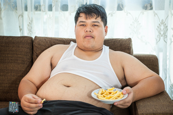 Pigro maschio in sovrappeso seduto con fast food
 - Foto, immagini