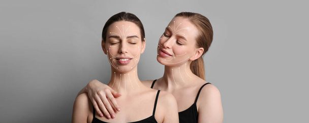 Jonge vrouwen met pijlen voor masseren op gezichten tegen grijze achtergrond - Foto, afbeelding