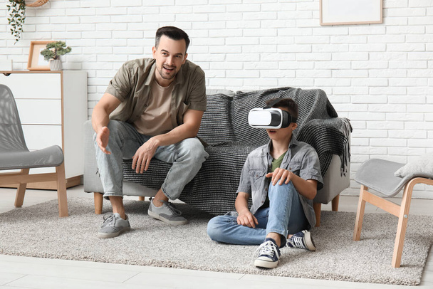 Отец и его маленький сын в очках виртуальной реальности веселятся дома - Фото, изображение