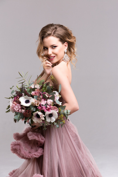 Mujer con el pelo largo rizado en un vestido rosa y flores de boda
. - Foto, imagen