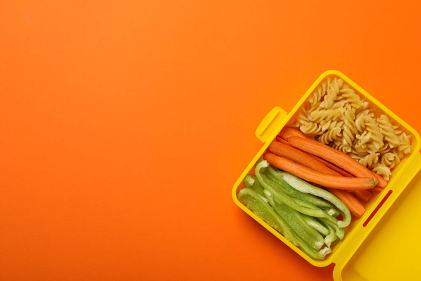 Желтая коробка с едой на оранжевом фоне - Фото, изображение