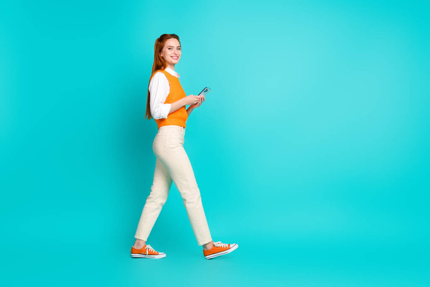 Profile photo of charming lovely woman wear trendy orange clothes walk empty space isolated on cyan color background. - Foto, Imagen