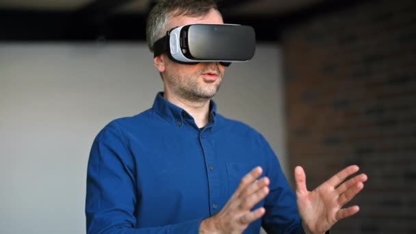 Ο άνθρωπος χειρονομεί ενώ χρησιμοποιεί ακουστικά Εικονικής Πραγματικότητας σε ένα γραφείο - Πλάνα, βίντεο