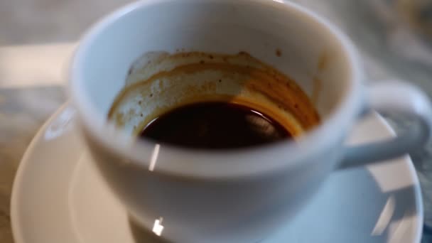 Κοντινό πλάνο ενός φλιτζανιού εσπρέσο σε ένα τραπέζι σε ένα καφέ - Πλάνα, βίντεο