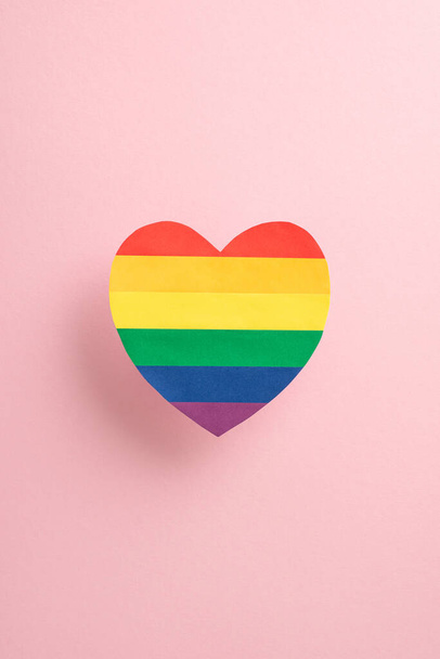 Яркий вертикальный радужный символ сердца на мягком розовом фоне, символизирующий любовь и единство в течение месяца Гордости - Фото, изображение
