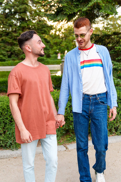 LGBT pár má klidný okamžik, ruce sepjaté v bujném parku. - Fotografie, Obrázek