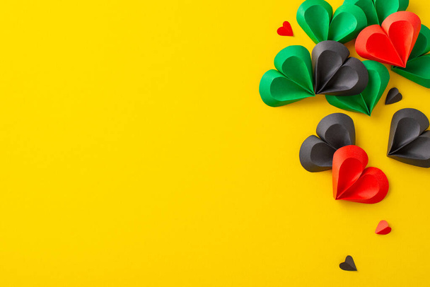 A vibrant display of paper hearts in green, black, and red on a yellow backdrop, symbolizing unity and freedom commemorating Juneteenth - Photo, Image