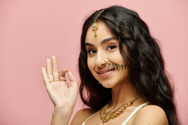 Jeune femme indienne aux cheveux longs frappe une pose mettant en valeur ses bijoux. - Photo, image