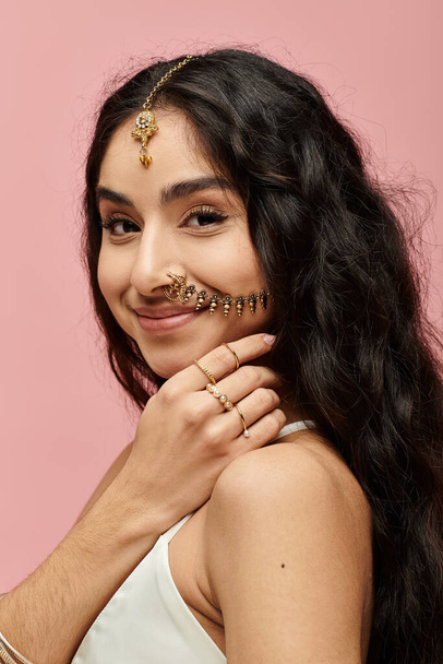 Young indian woman with nose ring striking a pose against pink backdrop. - Photo, Image