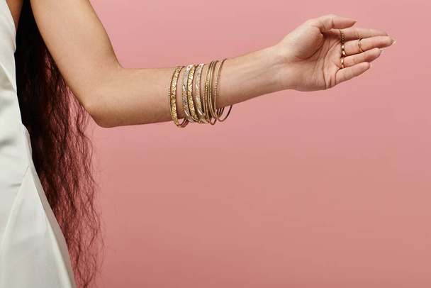 Jeune femme indienne présentant des bracelets dorés et des vêtements blancs. - Photo, image