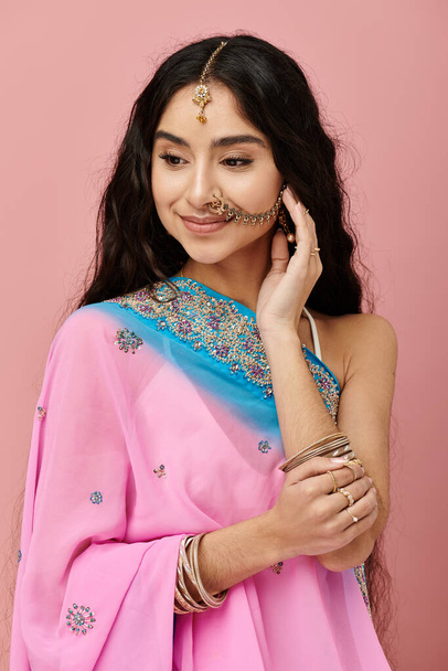 Elegancka Hinduska kobieta w tętniącym życiem różowym sari z wdziękiem pozowała. - Zdjęcie, obraz