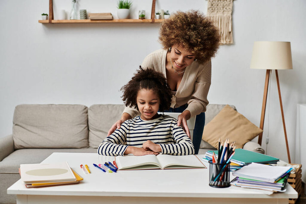 Glückliche afroamerikanische Mutter und Tochter lernen gemeinsam zu Hause und konzentrieren sich auf die Hausaufgaben. - Foto, Bild