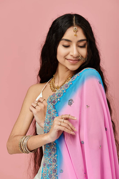 Młoda Hinduska kobieta w tętniącym życiem sari pozuje elegancko. - Zdjęcie, obraz