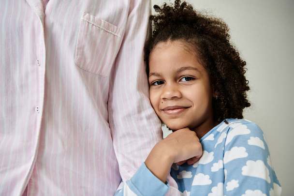Une mère et une fille afro-américaines en pyjama confortable posent joyeusement ensemble sur un fond gris. - Photo, image