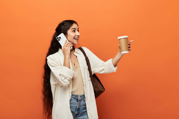 Κομψό ινδική γυναίκα κρατώντας φλιτζάνι καφέ, μιλώντας στο τηλέφωνο. - Φωτογραφία, εικόνα
