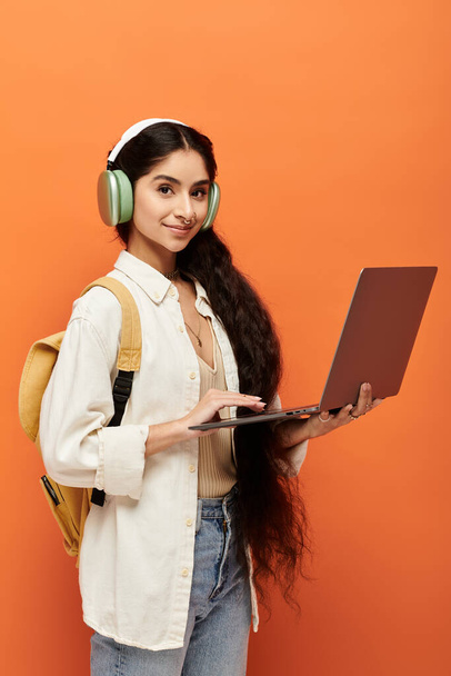 ヘッドフォンを介してノートパソコンや音楽に従事する若いインドの女性. - 写真・画像