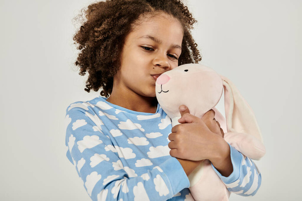 Молода дівчина в піжамі ласкаво обіймає фаршировану тварину - Фото, зображення