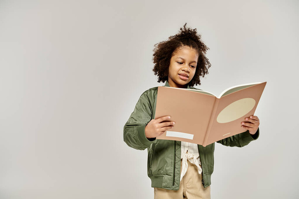 Una bambina assorta nella lettura di un libro su sfondo bianco. - Foto, immagini