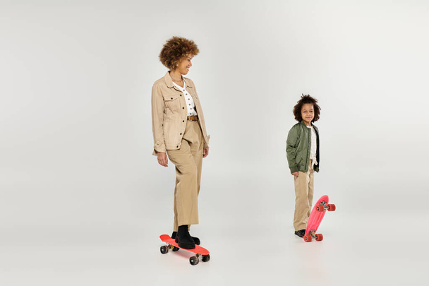 Curly Afro-Amerikaanse moeder en dochter in stijlvolle kleding, staan vol vertrouwen naast elkaar op skateboards. - Foto, afbeelding
