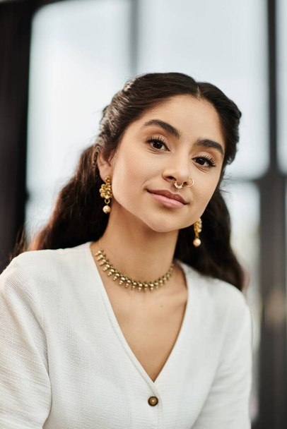 A young indian woman exudes elegance in a white shirt and gold jewelry. - Photo, Image