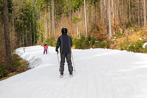 горнолыжный спуск лыжниками в солнечный день. Вид сверху. Активный отдых, школьные каникулы - Фото, изображение