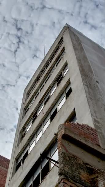 Low angle time lapse vídeo of empty old disused concrete building with clouds moving in the sky, El Poblenou, Barcelona, Espanha em vertical - Filmagem, Vídeo