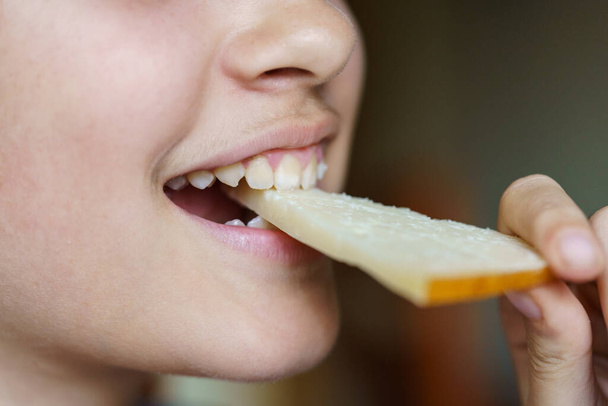 Крупный план счастливой анонимной девочки-подростка, кушающей свежий сыр дома - Фото, изображение