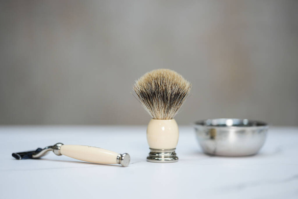 Un cepillo para aplicar crema de afeitar, con un mango de afeitar al lado - Foto, imagen