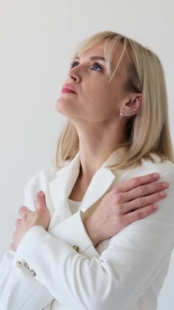 Egy szomorú fehér nő portréja depresszióban és gyászban, fehér háttérrel. Érzelmi stressz és frusztráció. Függőleges videó. - Felvétel, videó