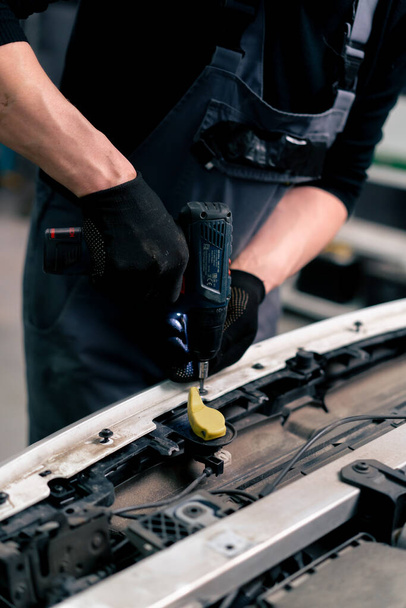 Nahaufnahme an einer Tankstelle Kfz-Mechanikermeister zieht die Schrauben im Inneren des Autos mit einem Bohrer fest - Foto, Bild