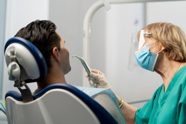 In una clinica dentistica un ortodontista soffia i denti per esaminare la cavità orale - Foto, immagini