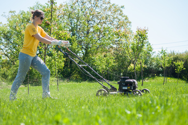 Young female in yard - pushing grass trimming lawnmower - Fotografie, Obrázek