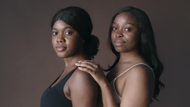Πορτρέτο δύο νεαρών Αφροαμερικανών γυναικείων μοντέλων που φορούν μινιμαλιστικά σουτιέν ποζάρουν μαζί για την κάμερα στο στούντιο - Πλάνα, βίντεο