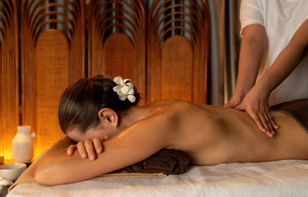 Кавказька жінка-клієнт насолоджується розслабляючим антистресовим спа-масажем і бродить з дозвіллям краси шкіри відпочинку в теплому освітленні свічок навколишнього салону спа в розкішному курорті або готелі. Тихіше - Фото, зображення