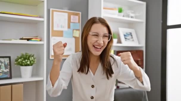 Excited young brunette girl raising arms in success, beaming with pride at laptop victory in office! - Footage, Video