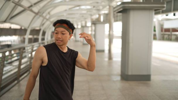 Fiksu komea tanssija liikuttaa käsiään tanssiessaan hip hop musiikkia. Ammattimainen aasialainen hipster yllään kuulokkeet kävellessään pitkin käytävää hämärä tausta. Ulkoilu 2024. Sujuvasti.. - Valokuva, kuva