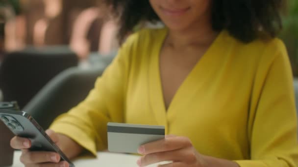 Κοντινό πλάνο νεαρή Αφροαμερικανή γυναίκα που κατέχουν smartphone κινητό τηλέφωνο τραπεζική κάρτα ψώνια πληρωμής αγοράσουν ευτυχισμένη γυναίκα ικανοποιημένοι μετρητά πιστωτικό νόμισμα χρεωστικά χρήματα αγορά online gadget συναλλαγή - Πλάνα, βίντεο