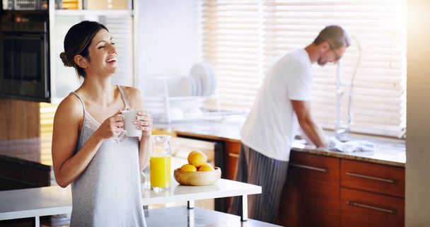 Couple, cuisine et café le matin pour coller, femme heureuse et homme nettoyer la vaisselle. Rattrapage, pause et histoire drôle avec boisson chaude, amour et soins avec confiance dans le mariage pour la routine à la maison. - Photo, image