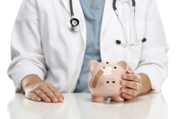 Doctor Holding Caring Hand on a Piggy Bank with Bandage - Photo, Image