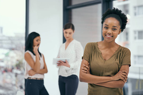 Business, portrait and black woman with arms crossed in office for training, career goals or new job opportunity. Ambition, smile and employee with colleagues for teamwork, support or happiness. - Photo, Image