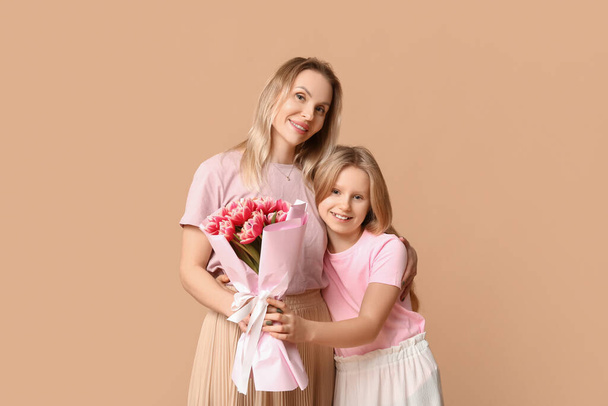 Nettes kleines Mädchen mit Mama und Blumenstrauß zum Muttertag auf beigem Hintergrund - Foto, Bild