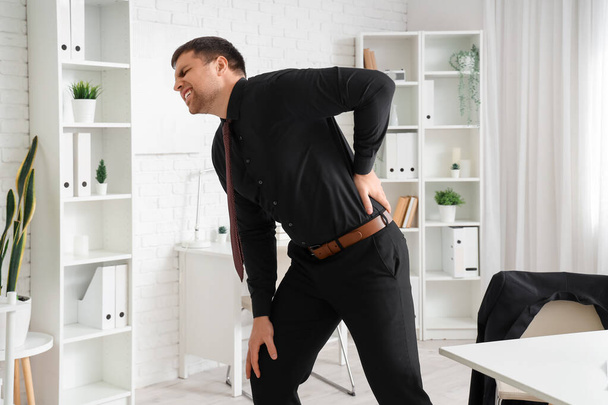 Бізнесмен, який страждає від болю в спині в офісі
 - Фото, зображення