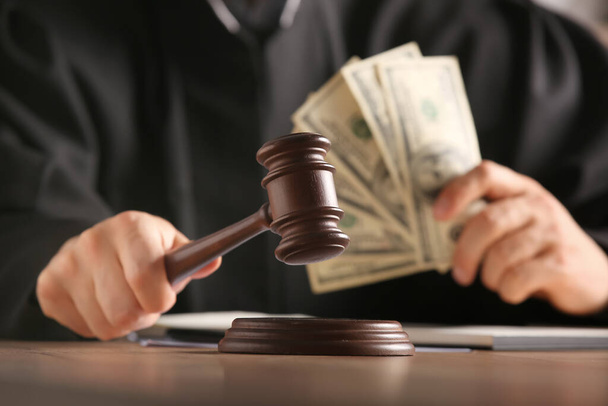 Мужчина судья с молотком и деньгами за столом в офисе - Фото, изображение