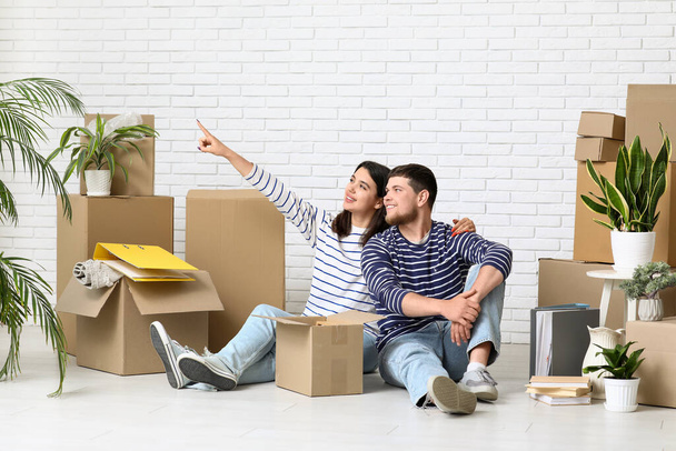 Молодая женщина указывает на что-то рядом с ее мужем и вещи в их новом доме - Фото, изображение