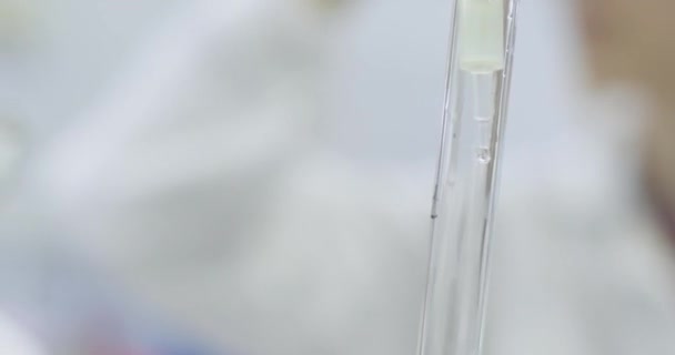 Goteo de líquido transparente en tubo de vidrio con pipeta en el primer plano del laboratorio médico. Realización de experimentos químicos con fluidos en la clínica - Imágenes, Vídeo
