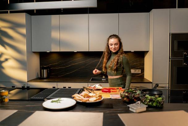 une jeune fille amoureuse dans une robe verte dans la cuisine préparer le dîner jour heureux - Photo, image