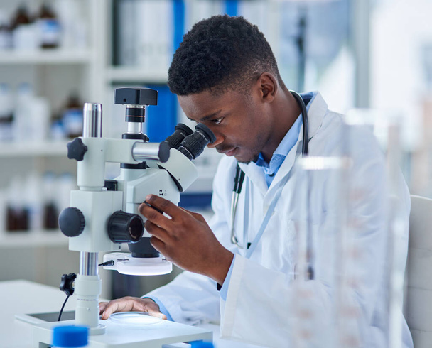 Tudomány, kutatás és fekete ember mikroszkóppal a biotechnológia, vizsgálat vagy orvosi mérnöki laborban. Analízis, laboratóriumi technikus vagy tudós ellenőrzi a vakcina mintáját gyógyszerészeti vizsgálat céljából - Fotó, kép