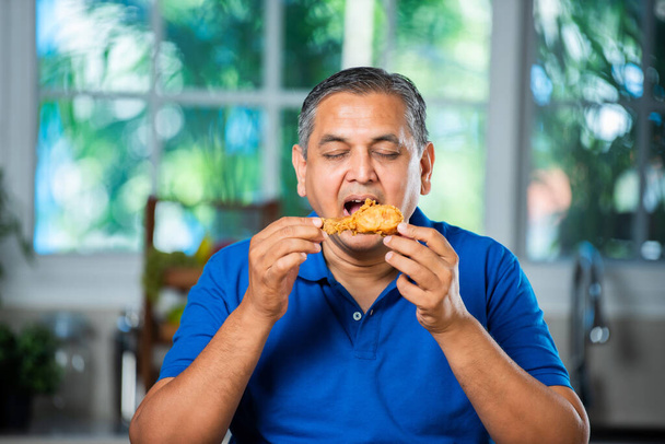 Asiatique indien moyen âge homme manger frit poulet jambe morceau - Photo, image
