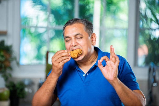 Ασιάτης μεσήλικας που τρώει τηγανητό κοτόπουλο - Φωτογραφία, εικόνα